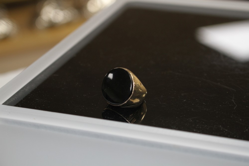 A yellow metal (stamped 9ct) and black onyx set circular signet ring, size L, gross weight 9 grams.